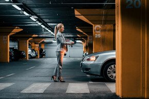  Elegante Geschäftsfrau mit Autoschlüsseln vor einem Auto in der Tiefgarage | © bnenin - AdobeStock
