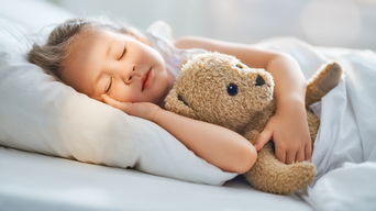 Kind schläft seitlich im Bett mit Teddybär in der linken Hand und rechte Hand auf dem Kissen | © bösch heizung.klima.lüftung