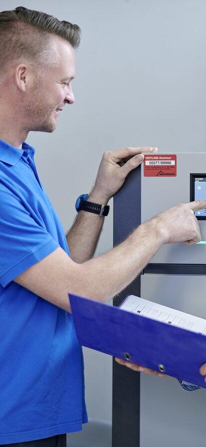 Techniker erklärt einer Kundin die Bedienung einer modernen bösch Heizungsanlage in einem Technikraum | © bösch heizung.klima.lüftung