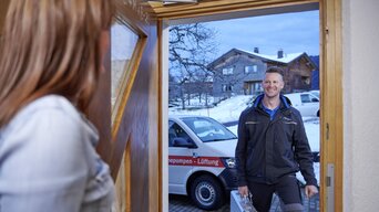 Kundin macht von innen die Haustür für einen Techniker vom bösch Kundendienst auf | © bösch heizung.klima.lüftung