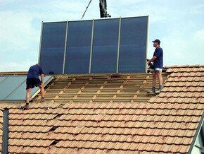 Zwei bösch Techniker installieren Solaranlage auf einem Ziegeldachhaus mit Hilfe eines Krans | © bösch heizung.klima.lüftung