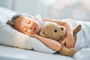 Kind schläft seitlich im Bett mit Teddybär in der linken Hand und rechte Hand auf dem Kissen | © bösch heizung.klima.lüftung