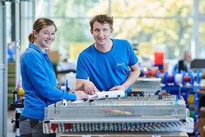 zwei bösch Elektrotechniker lächeln während sie an ihrem Projekt in der Werkstatt arbeiten und die Kamera anschauen