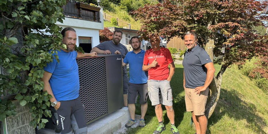 Der Betreiber sowie mehrere Techniker von bösch und dem beteiligten Installateur stehen gemeinsam vor der installierten MOZART15 Propan Wärmepumpe von bösch im Garten eines Einfamilienhauses. | © bösch