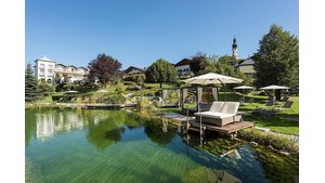 Wellness-Liege auf einem Steg am See im Garten mit Hotel im Hintergrund. | © Hotel Gmachl GmbH