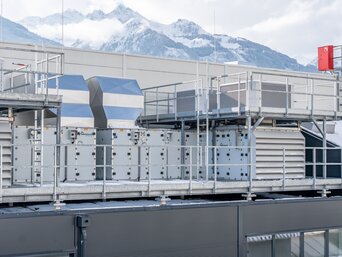 Dachanlage bei Senoplast mit SHC-System Gesamtansicht der Lüftungs- und Kühleinheiten des Sustainable Hall Conditioning Systems auf dem Dach des Senoplast-Werks in Piesendorf vor Alpenkulisse