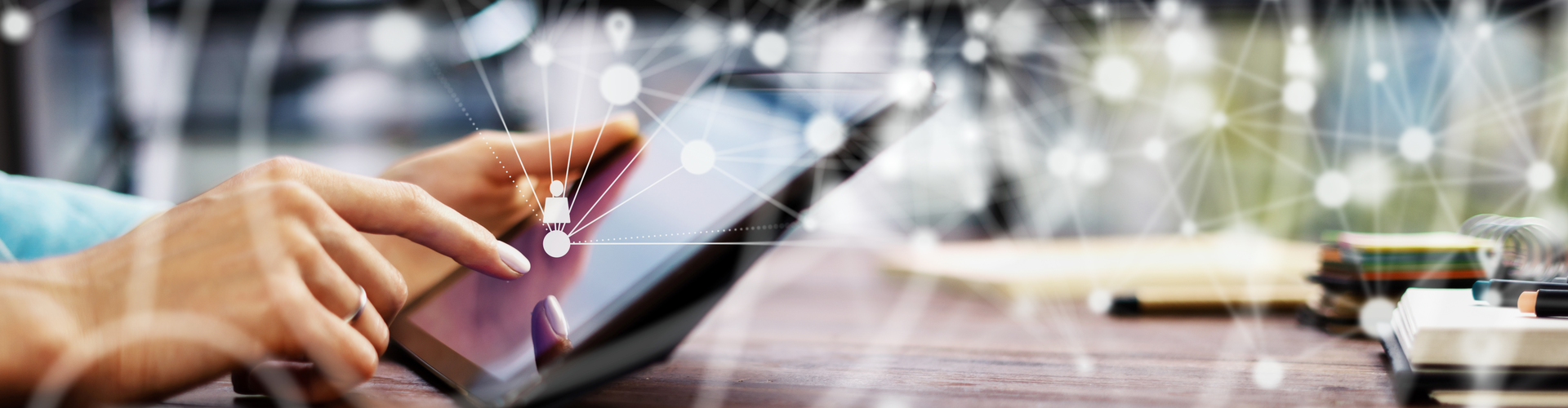 Nahaufnahme der Hand einer Person, die auf einem Tablet tippt, mit scharfem Fokus auf den Fingerspitzen und einem unscharfen Hintergrund, der einen modernen Büroarbeitsplatz andeutet, beleuchtet durch sanftes, schimmerndes Lich